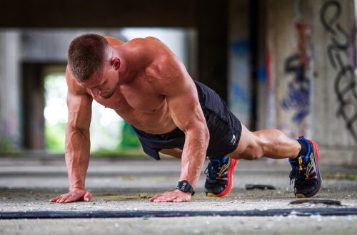 Shirtless caucasian man doing push-ups in an urban setting, showcasing strength and fitness.