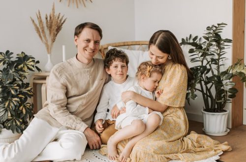Happy family of four enjoying quality time together in a cozy, plant-filled room.